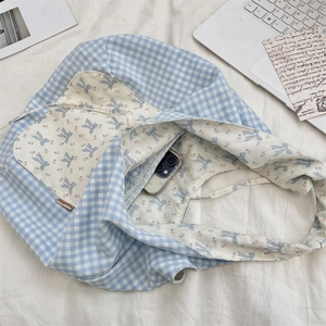 Détail du sac fourre-tout à fleurs et carreaux bleus avec un carnet en décor lifestyle