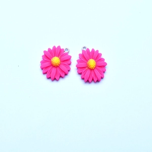 Macro view of pink resin sunflower pendants with silver rings for DIY jewelry making