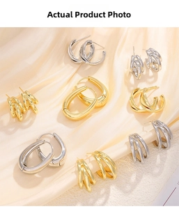 Close-up of assorted gold and silver huggie hoop earrings on soft silk fabric texture