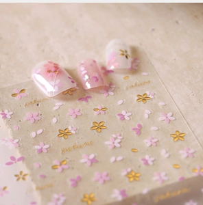 Detailed macro view of 3D embossed cherry blossom nail stickers with gold foil accents
