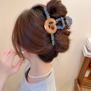 Détail de la pince à cheveux avec rayures noires et blanches et nœud marron