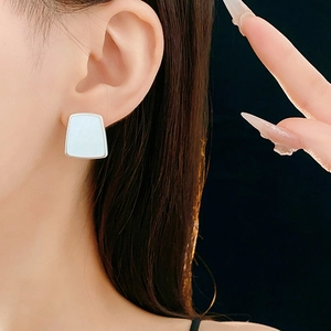 Vue macro d'une boucle d'oreille trapèze en résine avec bordure argentée sur l'oreille