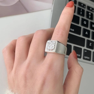 Detailed view of silver square signet ring with hammered texture worn on a hand