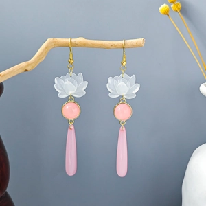 Close-up of pink lotus flower earrings with beaded tassels hanging on a branch