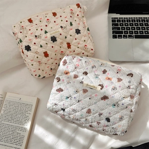Detailed close-up of quilted cosmetic bags with beige bear and white dog patterns