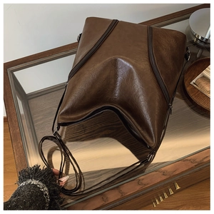 Macro detail of dark brown vintage oil wax leather bag with unique V-shaped zipper design