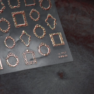 Macro detail of 3D embossed rose gold photo frame nail art stickers with metallic texture