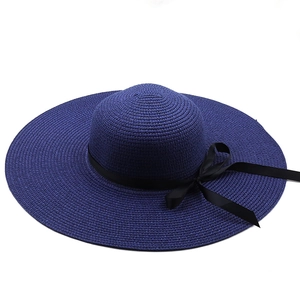Wide-brimmed navy blue summer straw hat with black ribbon bow and woven texture