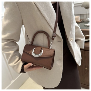 Détail du sac à main en cuir litchi marron avec boucle en croissant et bandoulière