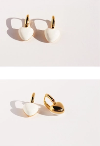 Macro detail of heart-shaped earrings showing gold finish and white enamel on both sides
