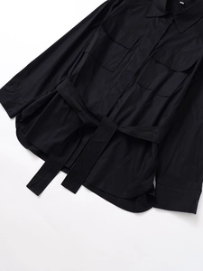 Detailed flat lay of black long sleeve utility shirt with waist belt and chest pockets