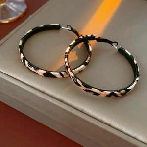 Détail de boucles d'oreilles créoles à imprimé léopard en cuir noir blanc et marron