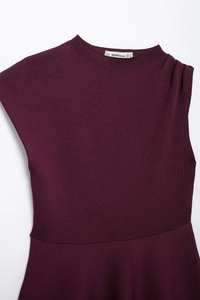 Detalle de vestido de punto rojo oscuro con cuello plisado y etiqueta de talla interior