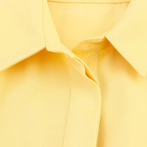 Detailed macro view of twill fabric texture and collar design on a yellow shirt dress
