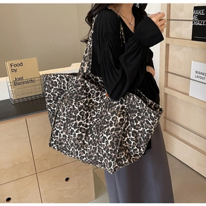 Detailed side view of leopard print canvas tote bag showing wide straps and side buckles