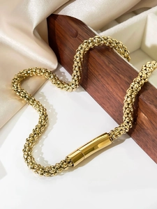 Detail of 6mm golden snake chain necklace with textured metal beads on white silk