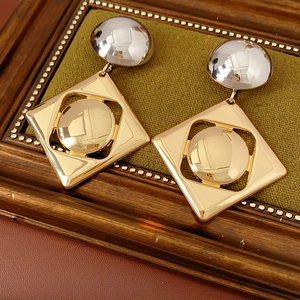 Detail view of geometric silver and gold earrings on a green velvet display tray