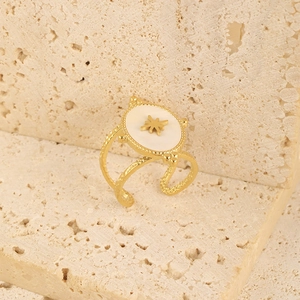 Detail of gold-plated open ring featuring a white oval shell with an eight-pointed star