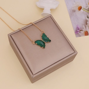Detail of a green butterfly pendant necklace on a gold chain displayed on a jewelry box