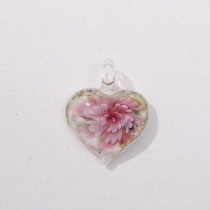 Macro detail of heart-shaped lampwork glass pendant with pink flower and gold foil