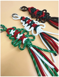 Close-up of handmade woven Christmas keychain charms with metallic rings and tassels