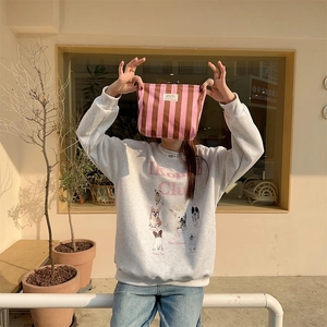 Pink and brown striped canvas makeup bag held by a model in a casual street style look