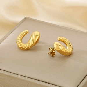 Detailed close-up of 18K gold plated irregular spiral hoop earrings on champagne silk fabric