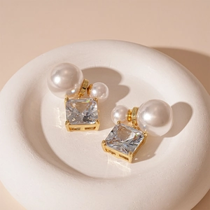 Détail de boucles d'oreilles perles double face avec zircon carré plaqué or