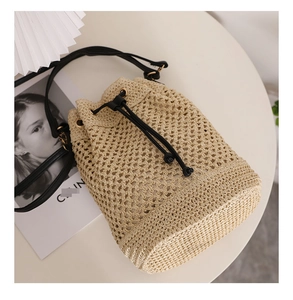 Top-down view of a beige woven bucket bag with black leather drawstring and strap detail