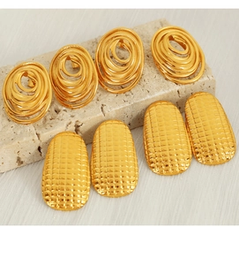Detail of gold titanium steel earrings with spiral and grid embossed textures on stone