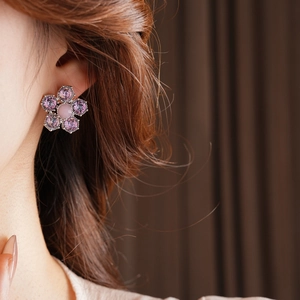 Gros plan d'une boucle d'oreille fleurie avec pétales en zircon violet et pierre œil-de-chat