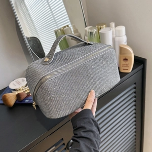 Close-up of silver-gray woven texture cosmetic bag with metallic handle on a vanity desk