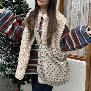Plush crossbody bag with blue dots paired with striped sweater and fleece vest detail
