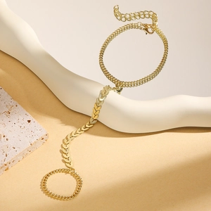 Detail of gold finger chain bracelet with bow, turquoise, and leaf chain design