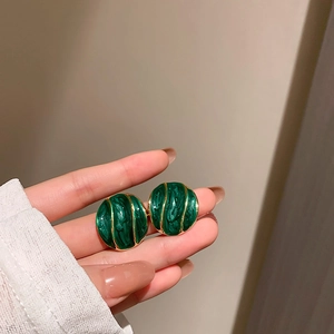 Macro shot of vintage gold-plated oval stud earrings with green enamel textures