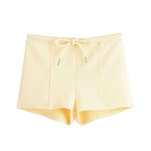 Close-up of light yellow casual shorts with elastic waist and white drawstring details