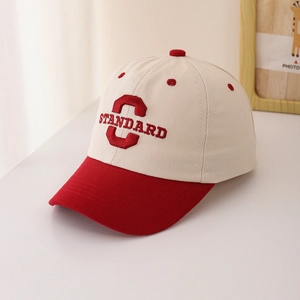 Close-up of red and beige kids baseball cap with C STANDARD 3D embroidery detail
