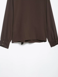 Detailed view of dark brown crepe blouse featuring double-button cuffs and textured hemline
