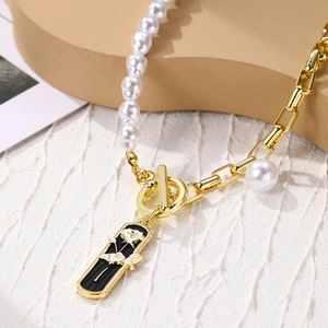Macro shot of asymmetric pearl and gold link chain with black rose relief cameo pendant