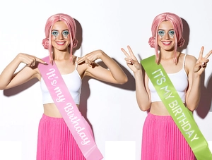Detail of pink and green satin birthday sashes with white It's My Birthday lettering