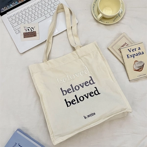 Detail of beloved letter embroidery on off-white canvas tote bag with wide strap