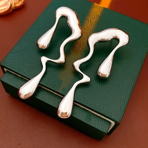 Gros plan de boucles d'oreilles argentées en métal liquide sur un coffret vert élégant
