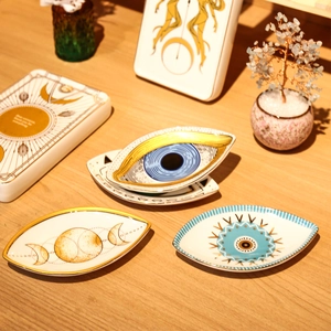 Ceramic evil eye jewelry trays with celestial moon phase motifs on wooden table
