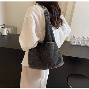 Close-up of black washed denim tote bag on model's shoulder in cafe setting