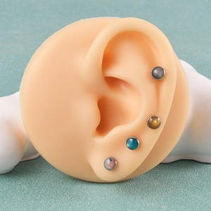 Vista dettagliata di quattro piercing labret tondi in pietra con texture su orecchio