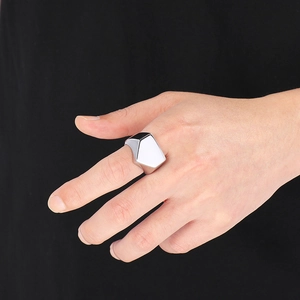 Macro side view of polished silver geometric pyramid ring on male hand with black backdrop
