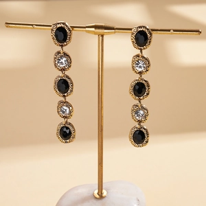Detailed view of vintage gold tassel earrings with hammered texture and black gemstones