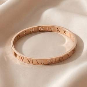 Macro shot of rose gold roman numerals hollow bangle on beige silk background