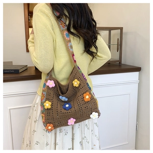 Detail of coffee crochet shoulder bag with 3D colorful 3D knit flowers on model