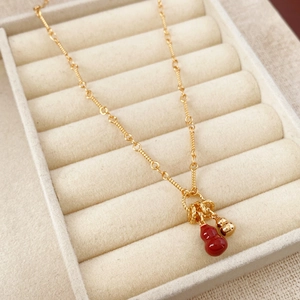Close-up of red gourd pendant necklace on 18k gold plated chain in jewelry box